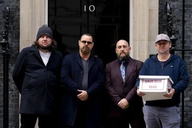 Four men outside the door of 10 Downing Street, one holding a box marked Save Our Seas; Danny Dyer is second from left in sunglasses